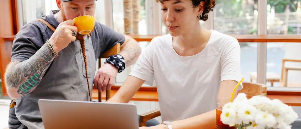 Two business owners planning at a laptop in a sunny cafe