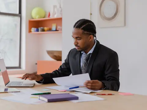 A business owner reading printed pages at a bright desk