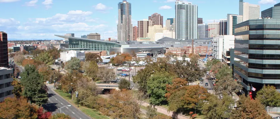 Downtown Denver's towers over Speer Boulevard and autumn trees