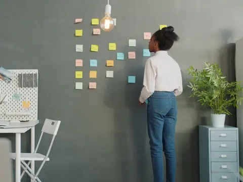 A woman pinning planning notes to an office wall