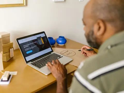 An owner sketching a plan beside his laptop at a desk