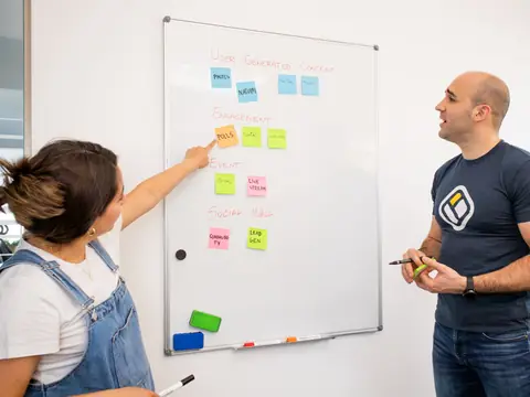 Two people planning at a whiteboard covered in sticky notes