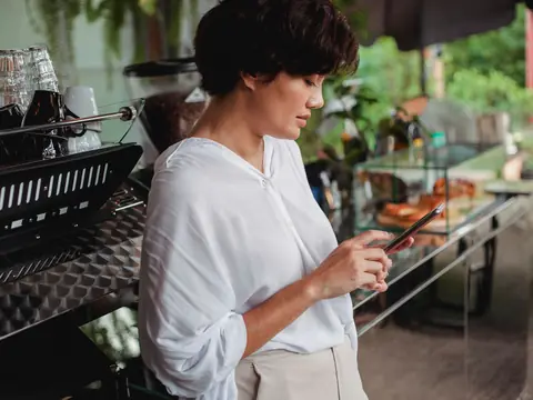 A cafe owner checking her phone behind the counter