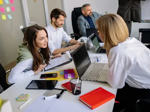 A small team going over a plan at laptops in a bright office