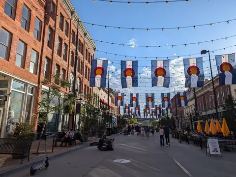 Restaurant patios and umbrellas along Larimer Square in Denver under Colorado flags