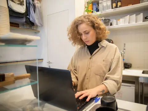 A shop owner working on her laptop behind the counter