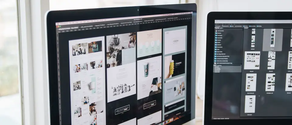 A designer's screens showing website layouts in a bright studio