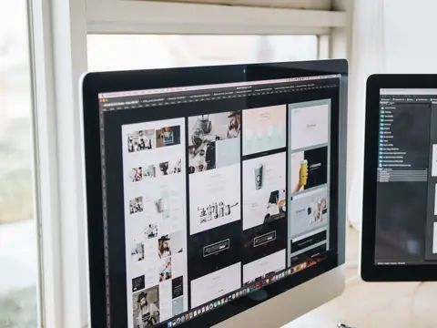 A designer's screens showing website layouts in a bright studio